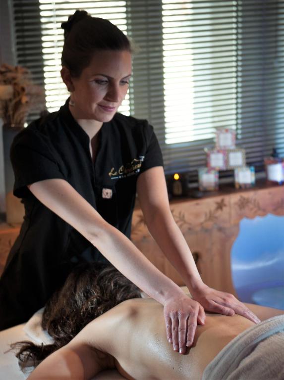 a woman sitting on a mans back getting a massage at Logis Hôtel et Spa Le Christiania in La Salle-les-Alpes