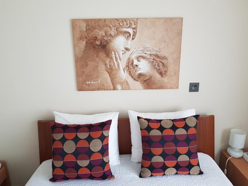 a painting hangs above a bed with two pillows at Next to the Airport in Moreira