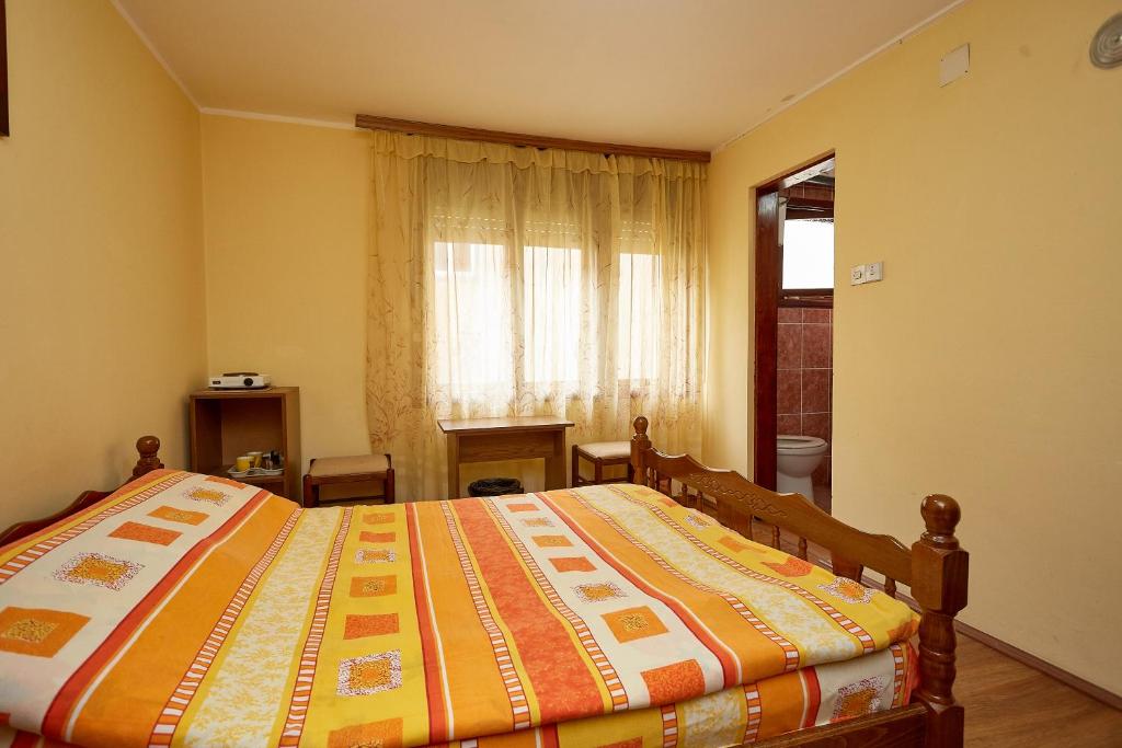 a bedroom with a bed with an orange and yellow quilt at Apartmani Malica in Soko Banja