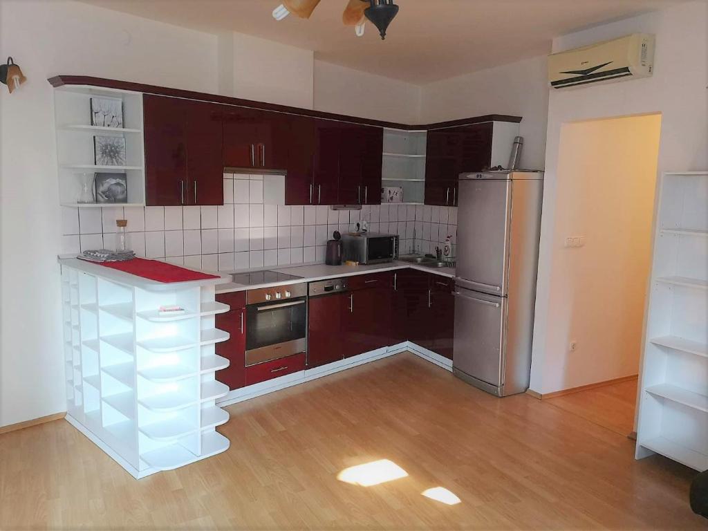 cocina con armarios marrones y nevera de acero inoxidable en Centrum - A. Apartman, en Pécs