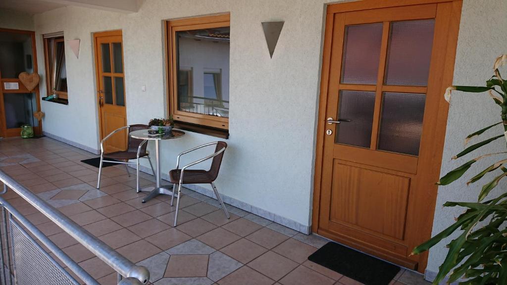 a porch with a table and chairs and a door at Gasthaus zum Löwen in Seckach