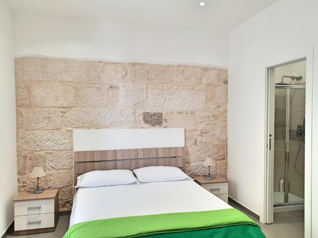 1 dormitorio con cama y pared de piedra en Blu Maris Sicilia Guesthouse, en Marina di Ragusa