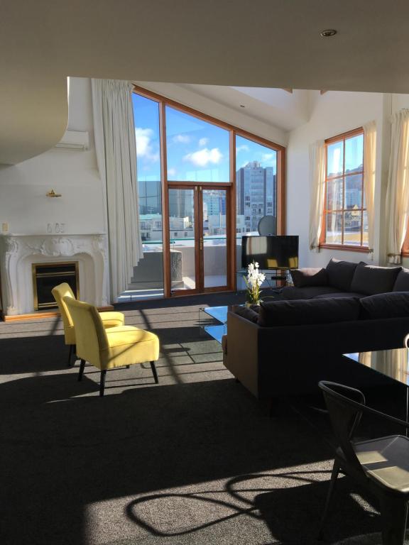 a living room with a black couch and a yellow chair at U Suites on Courtenay in Wellington