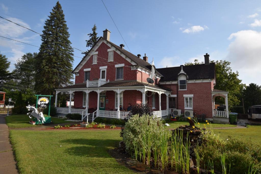 a large red brick house with a dog in the yard at Gil Ann in Saint-André-Avellin