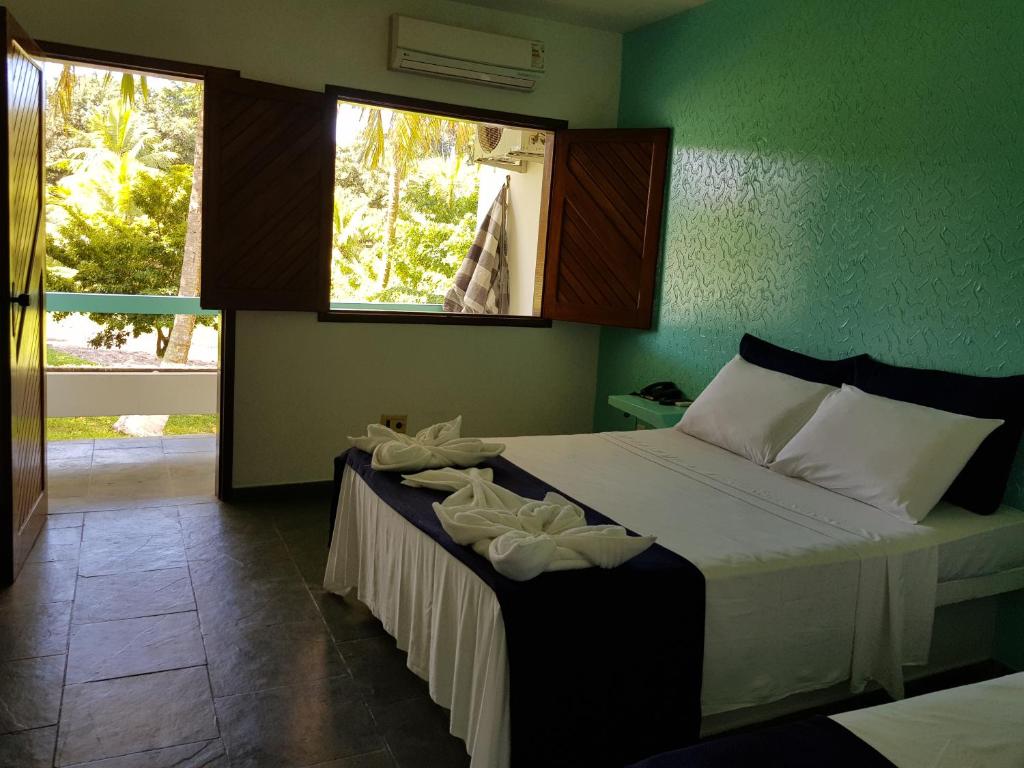 1 dormitorio con 1 cama con sábanas blancas y ventana en Pousada Sitio Paraiso, en Itacaré