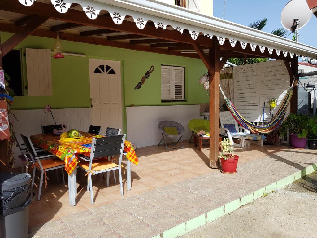 un patio con mesa y sillas bajo una pérgola en Bel Appartement - proche des plages de Sainte Anne, en Sainte-Anne