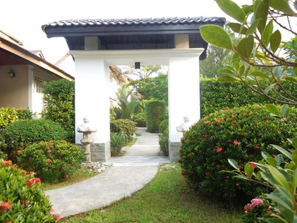 a white entrance to a garden with a walkway at Holiday Village And Natural Garden Resort in Karon Beach