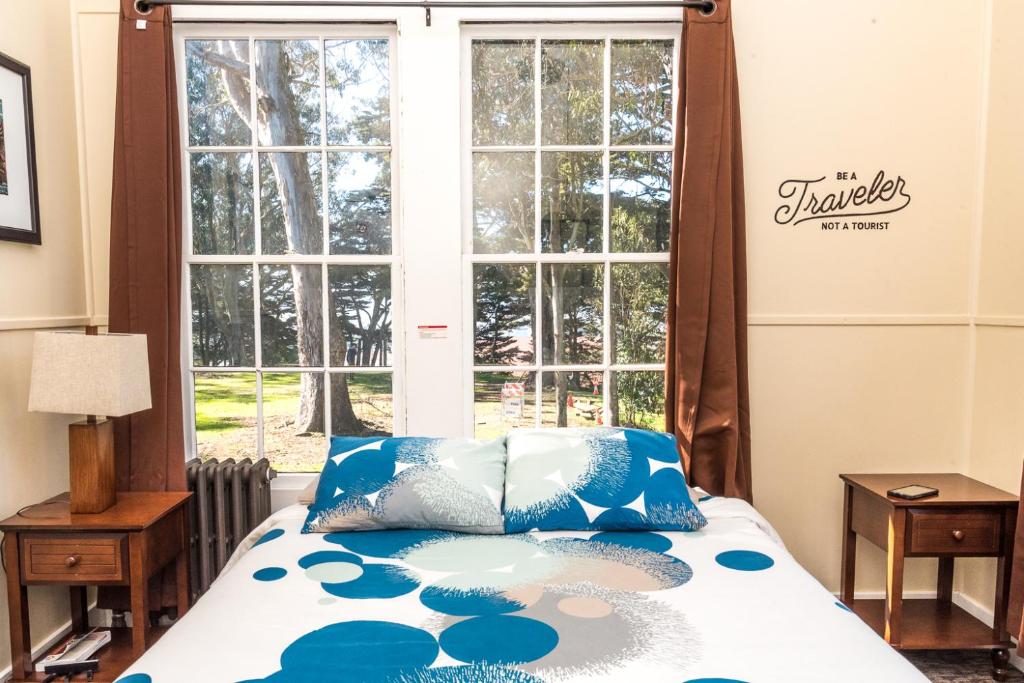 a bed with blue pillows in front of a window at HI San Francisco Fisherman's Wharf Hostel in San Francisco
