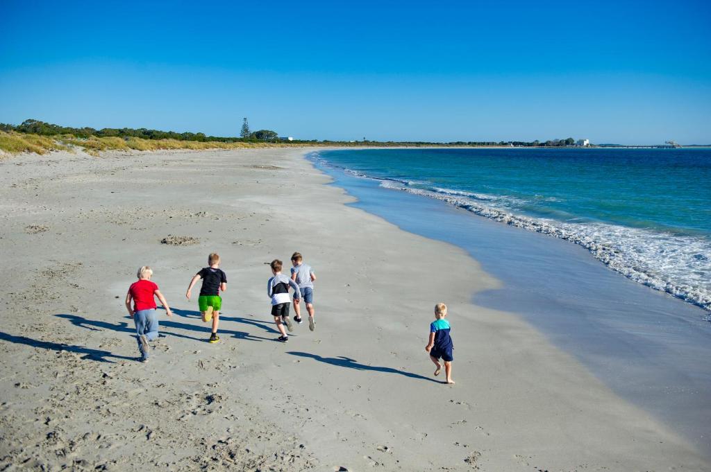 grupa dzieci spacerujących po plaży w obiekcie Discovery Parks - Woodman Point w mieście Coogee