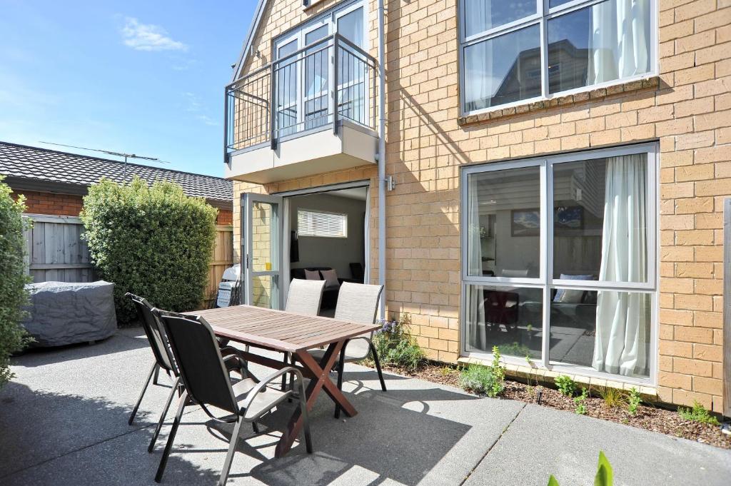 a wooden table and chairs in front of a building at Regents Villas - Christchurch Holiday Homes in Christchurch