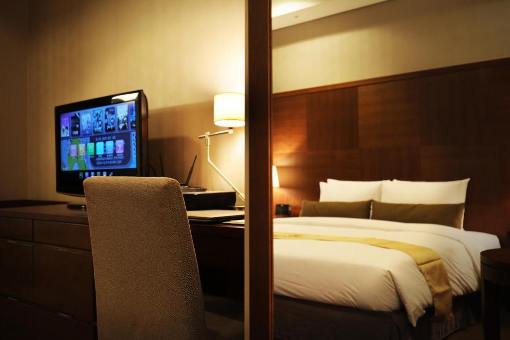 仁川にあるBridge Hotel Incheon Songdoのベッドとテレビが備わるホテルルームです。