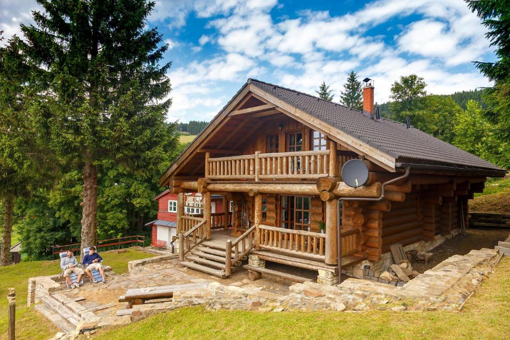 une grande cabane en rondins avec des personnes assises devant elle dans l'établissement Srub Midla a chata Bondovka, à Čenkovice