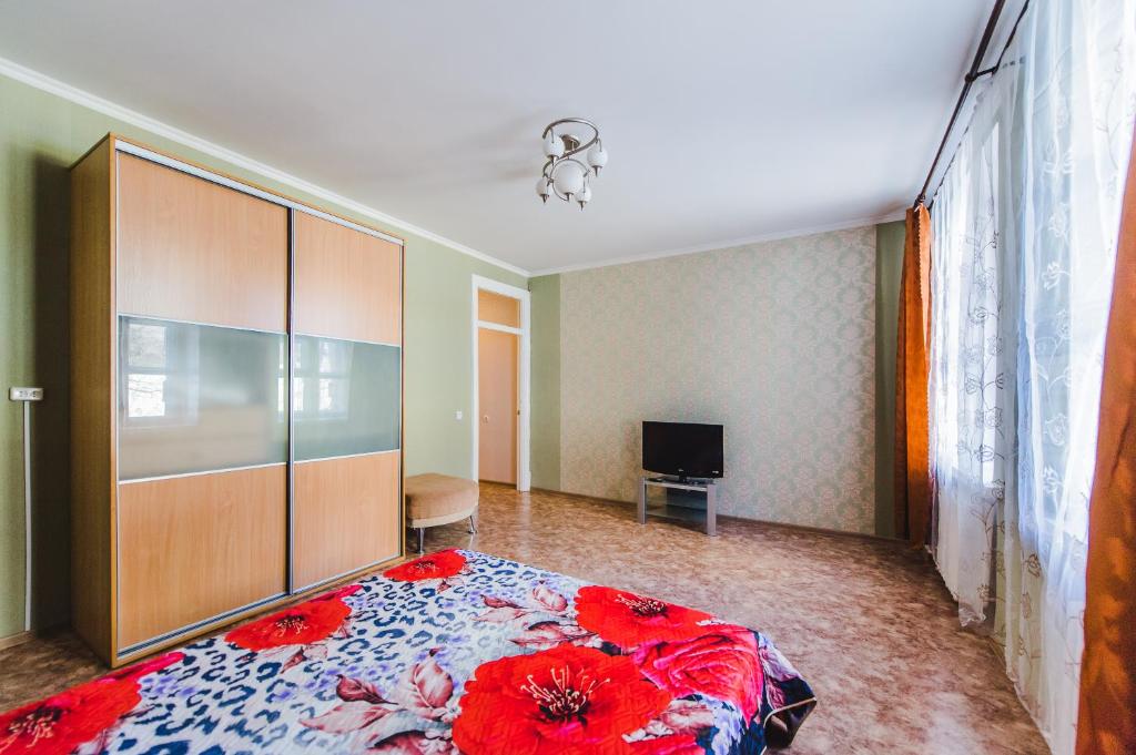 チタにあるDekabrist Apartment Leningradskaya 5のベッドルーム1室(赤い花の大きなベッド1台付)