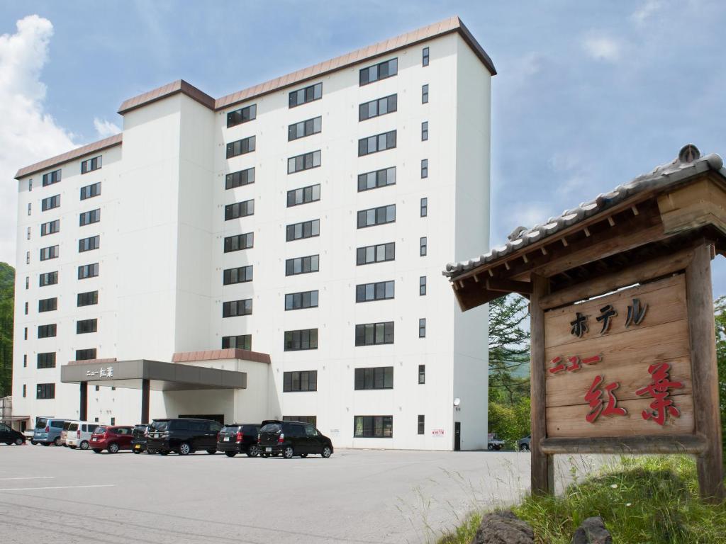 a large white building with a sign in front of it at Hotel New Koyo in Kusatsu