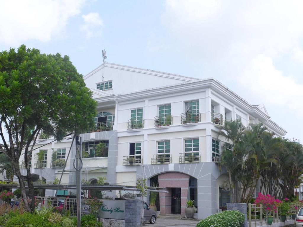 un edificio blanco con árboles delante de él en Wesberly Apartments, en Kuching