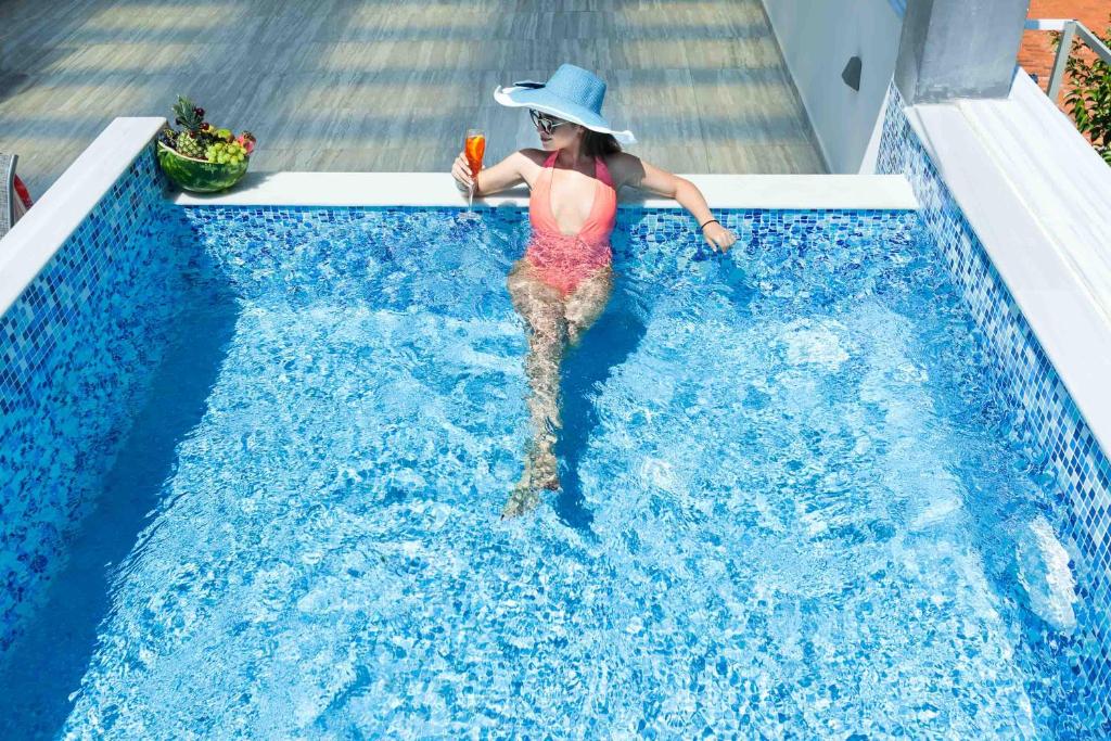 a woman in a hat is in a swimming pool at Nymphes Deluxe Accommodation Pefkochori in Pefkohori