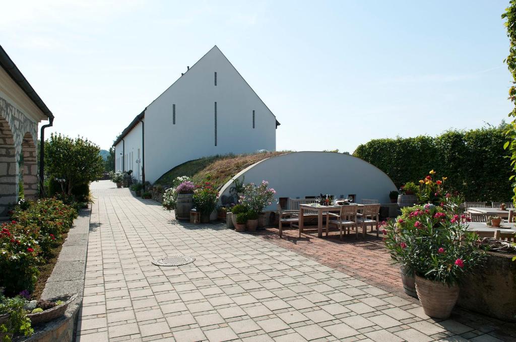 eine Terrasse mit Tischen und Blumen sowie ein Gebäude in der Unterkunft Remushof Jagschitz in Oslip