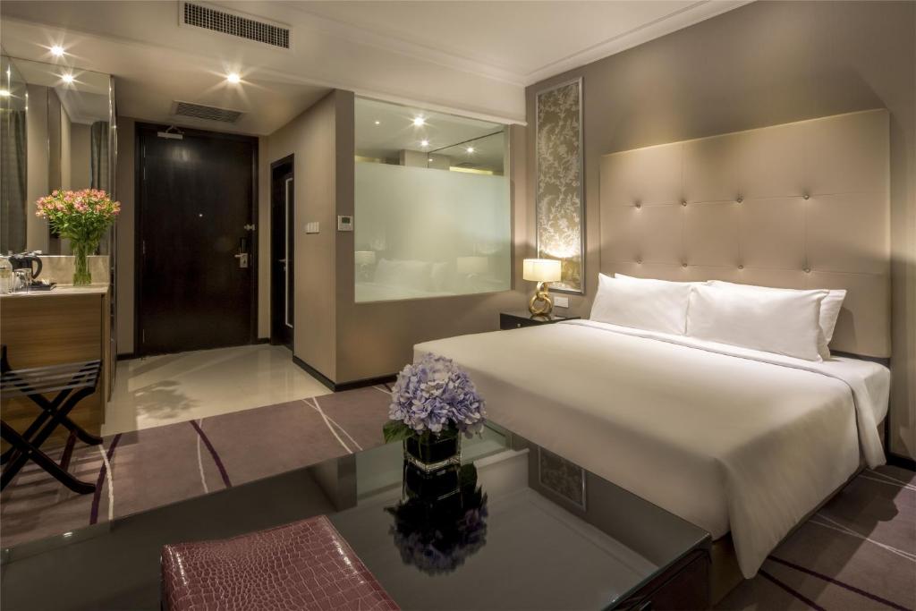 A polished bedroom pairs a large bed with a glass partition, desk, and reflective coffee table.