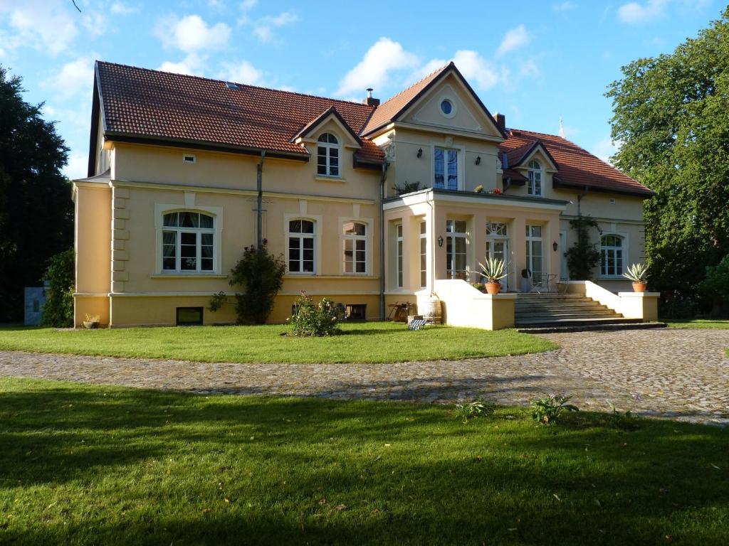 a large house with a grass yard in front of it at Exklusive Ferienwohnungen im Gutshaus Viezen in Bernitt