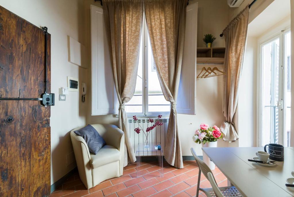 een woonkamer met een tafel, een stoel en een raam bij Ponte Vecchio Central Flats in Florence