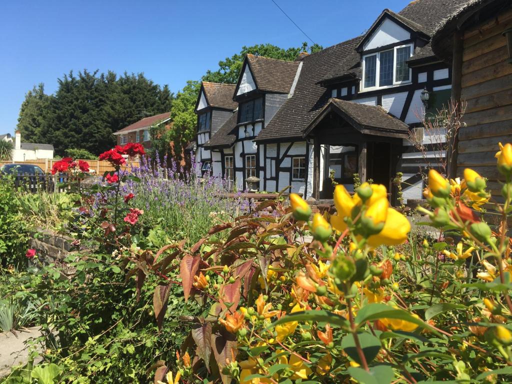 um jardim em frente a uma casa com flores em The Thatch Inn em Gloucester