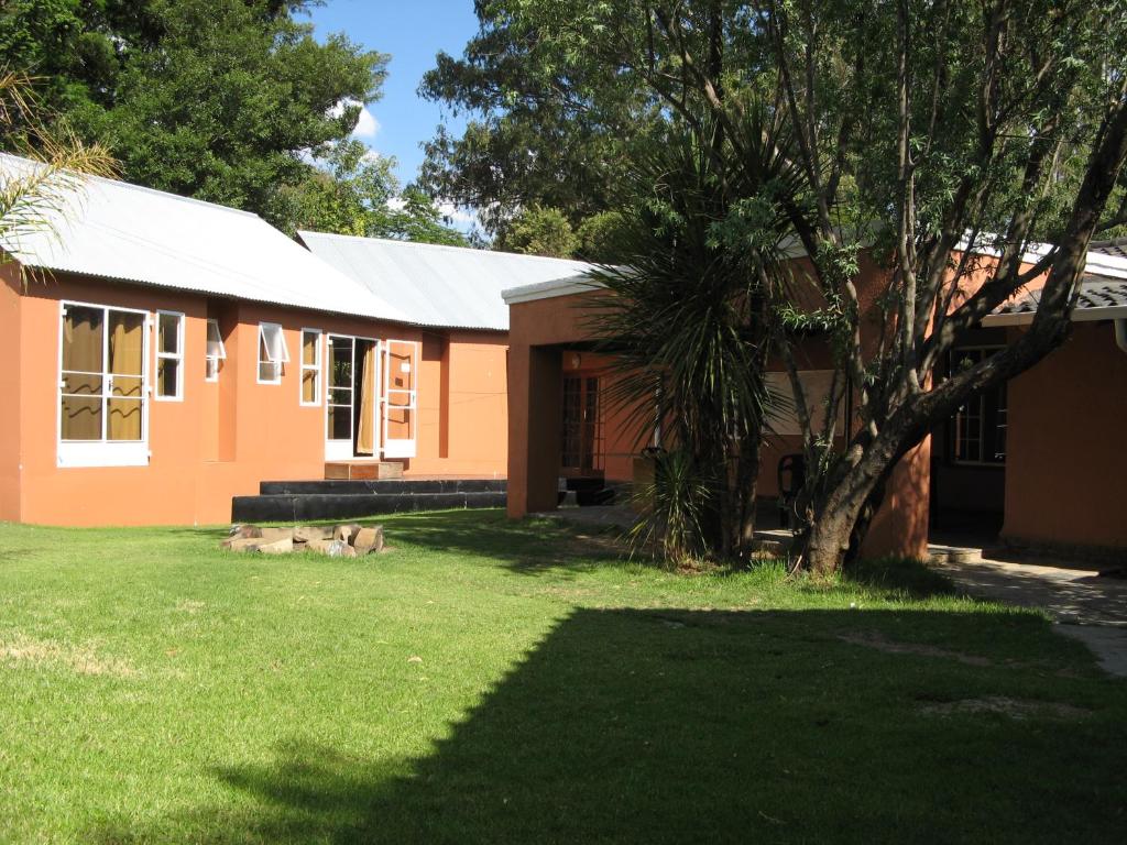 Johannesburg的住宿－Sleek Hostel，一座橘色房子,前面有一棵树
