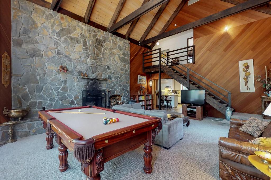 a living room with a pool table and a stone wall at Ski View Majesty in Truckee
