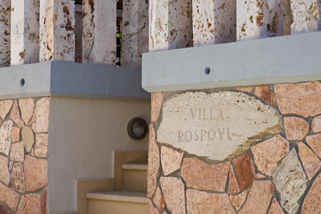 Una pared de piedra con una señal que dice renacer vil en Villa Rospovi, en Kaligata