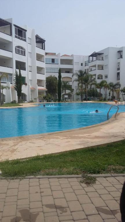 a large swimming pool in front of a building at location de vacance assilah marina golf in Asilah