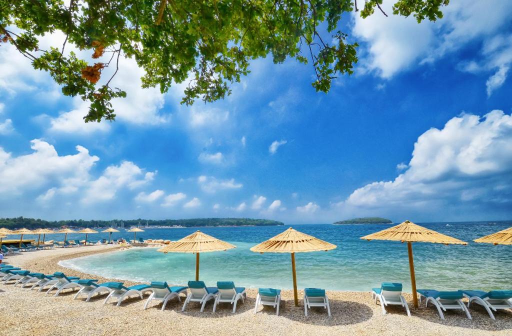 plaża z leżakami i parasolami oraz ocean w obiekcie Stone house Chiara Seaview w mieście Funtana