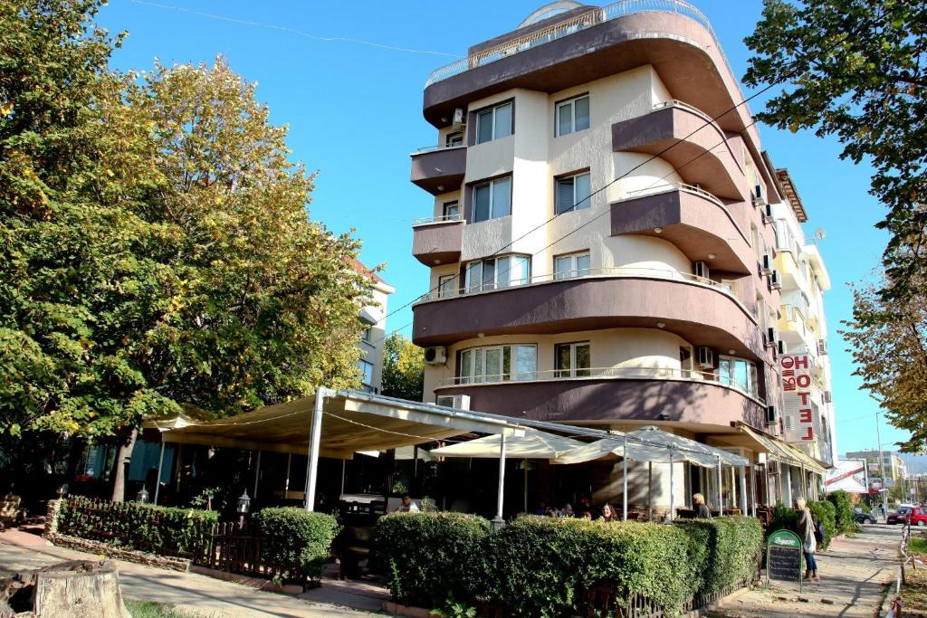 een hoog gebouw met een café ervoor bij Rio Family Hotel in Blagoevgrad