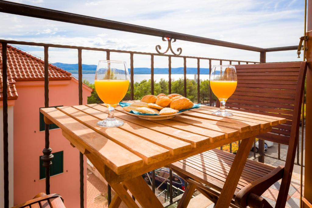 uma mesa de madeira com dois copos de sumo de laranja e pão em Apartments Vallum em Bol