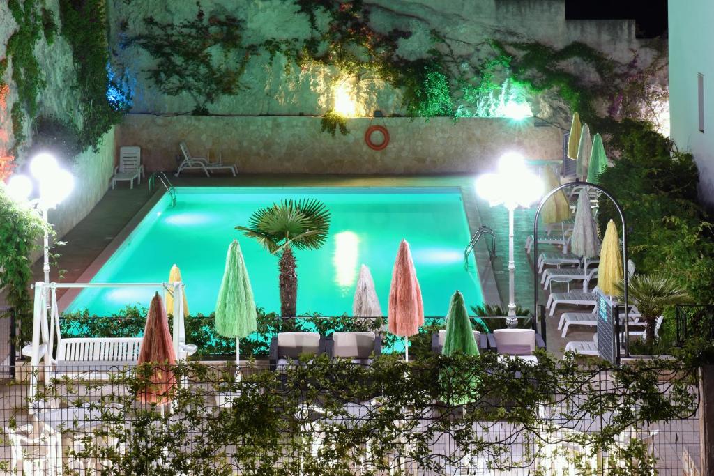a swimming pool with umbrellas and tables and chairs at Hotel Timiama in Peschici