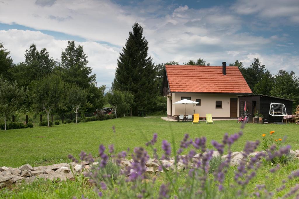 una casa con techo rojo en un campo en Stay In Touch, en Gospić
