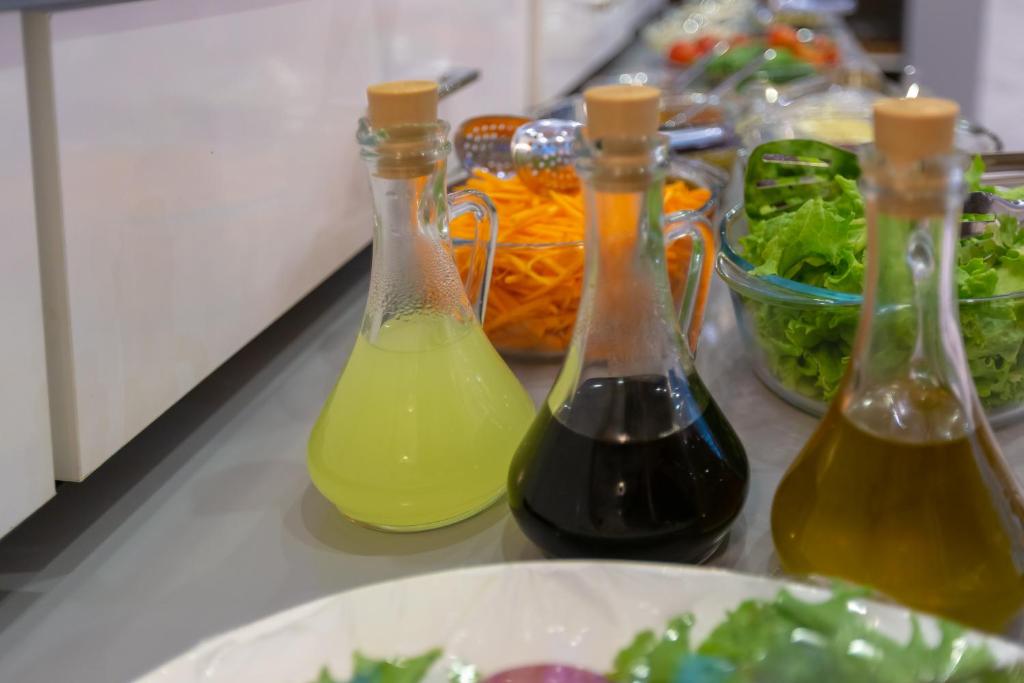 three bottles of wine on a counter with a plate of food at Aksent Hotel in Baku