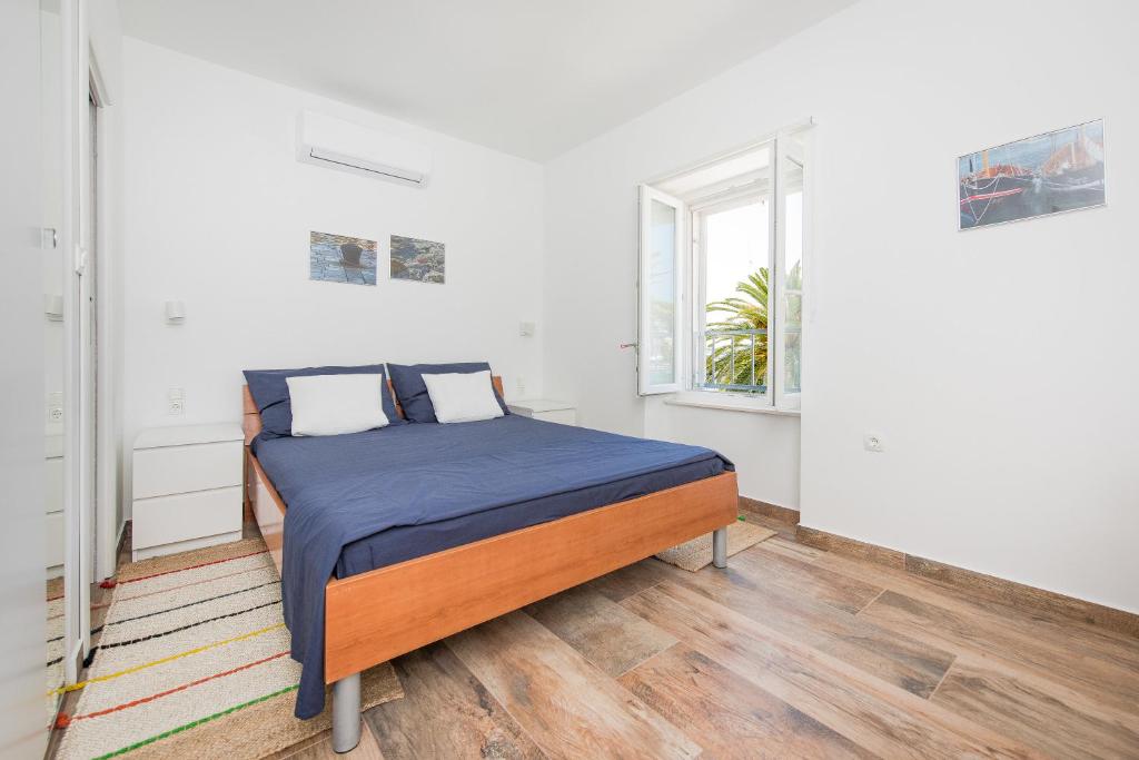 um quarto com uma cama com lençóis azuis e uma janela em Yacht harbor apartment em Hvar