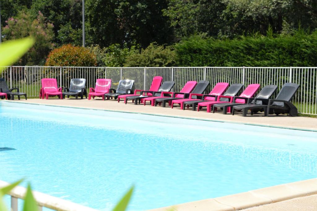 uma fila de cadeiras cor-de-rosa sentadas ao lado de uma piscina em Zenitude Hôtel-Résidences Bordeaux Aéroport Mérignac em Mérignac