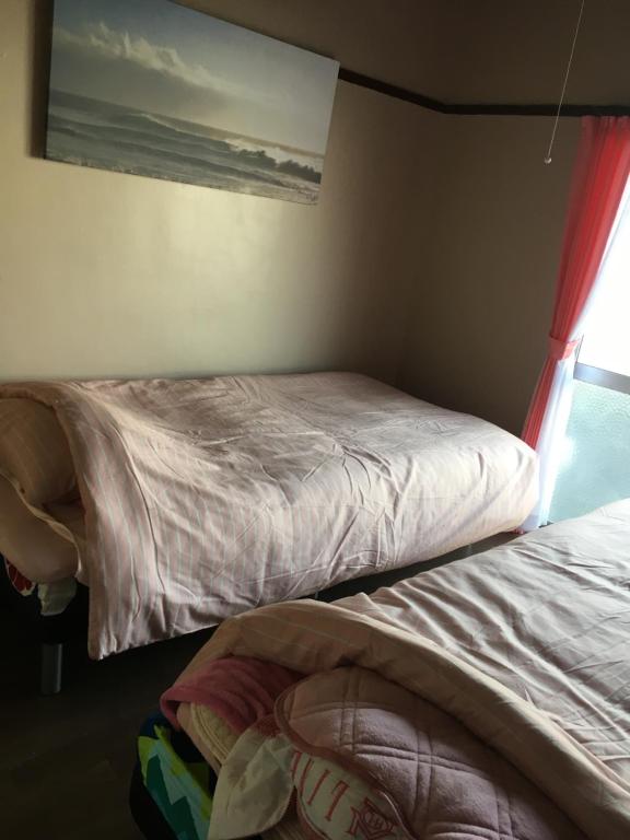 a bedroom with two beds and a window at Kurosaki Guesthouse 403 in Kitakyushu