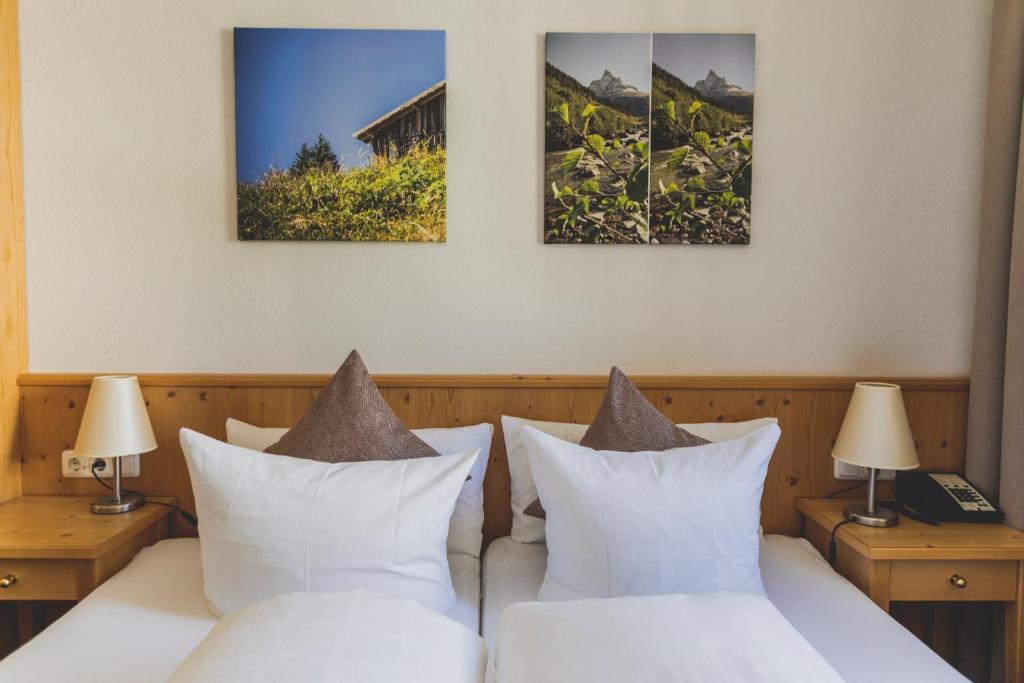a bedroom with two beds and two paintings on the wall at Hotel Montfort in Sankt Anton am Arlberg