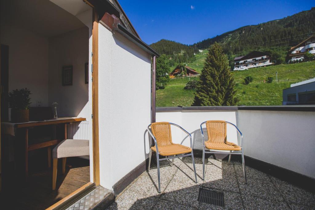 two chairs and a table on a balcony with mountains at Hotel Montfort in Sankt Anton am Arlberg