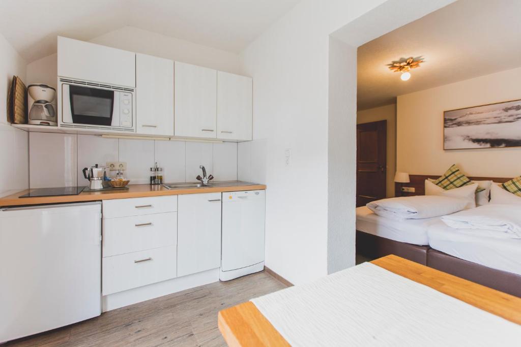 a kitchen with white cabinets and two beds in a room at Hotel Montfort in Sankt Anton am Arlberg