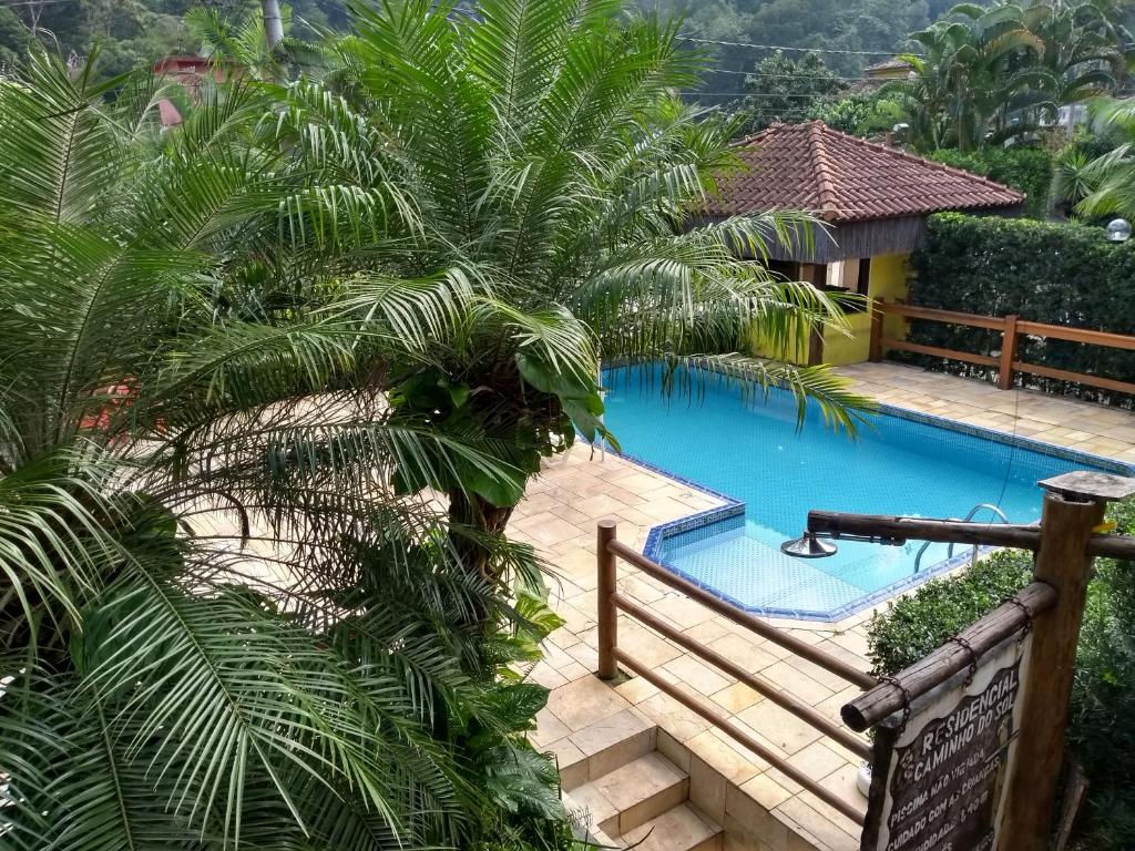 a swimming pool in a resort with palm trees at RC Sol de Boiçucanga - Suite in Boicucanga