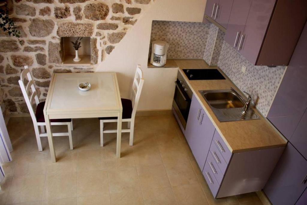una pequeña cocina con mesa, mesa y sillas en Apartment Cukarin A2 BOL-CENTER, Croatia en Bol