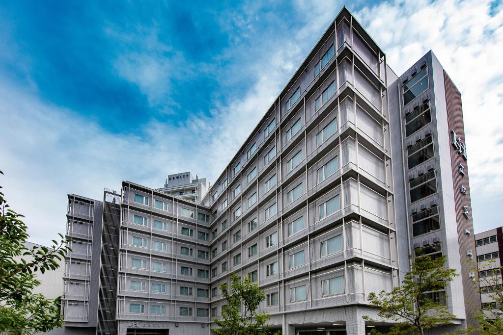 ein Bürogebäude mit blauem Himmel im Hintergrund in der Unterkunft Hotel Hewitt Koshien in Nishinomiya