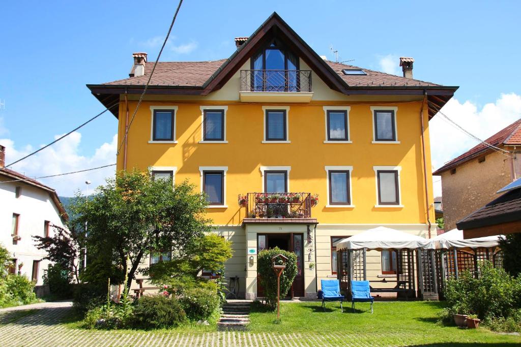 阿夏戈的住宿－Locanda Aurora-garnì，院子里的黄色房子,有两把蓝色的椅子