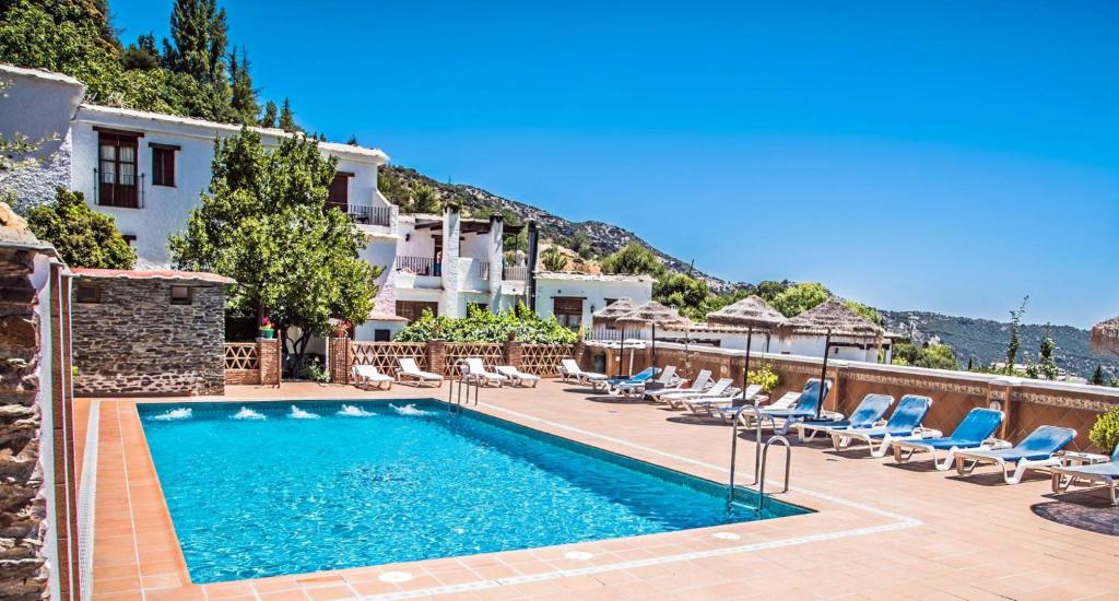 a swimming pool with lounge chairs and a hotel at Finca Los Llanos in Capileira