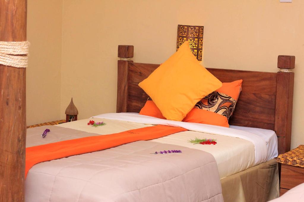 a bedroom with two beds with orange and yellow pillows at Lake Mulehe Gorilla Lodge in Kisoro