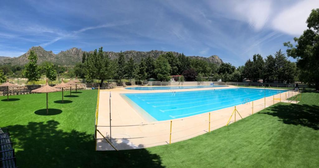 una imagen de una piscina con montañas en el fondo en Camping Pico De La Miel, en La Cabrera
