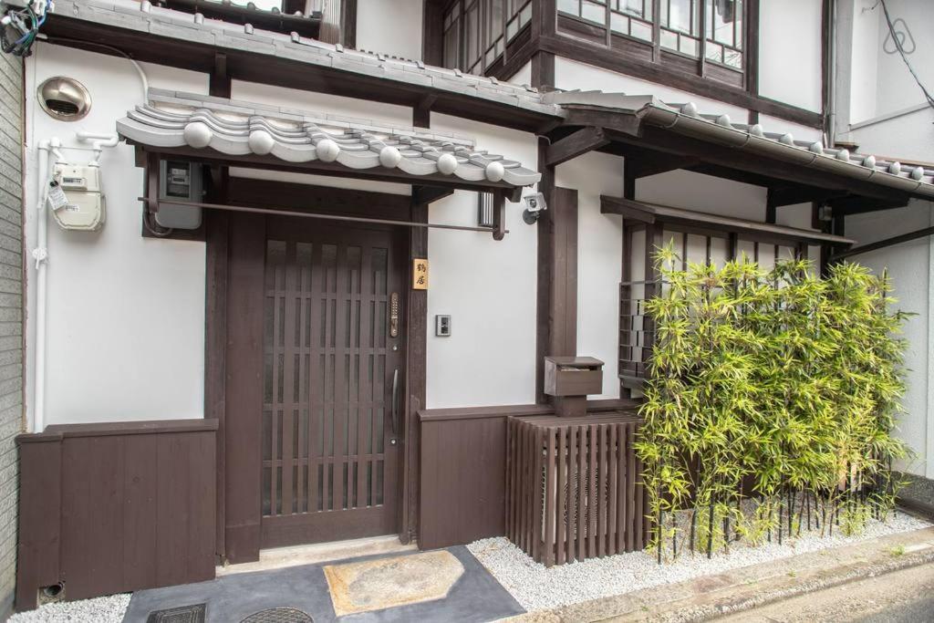 京都市にあるTsurui Goshonishi 鶴居御所西の茶色の扉と茂みのある家