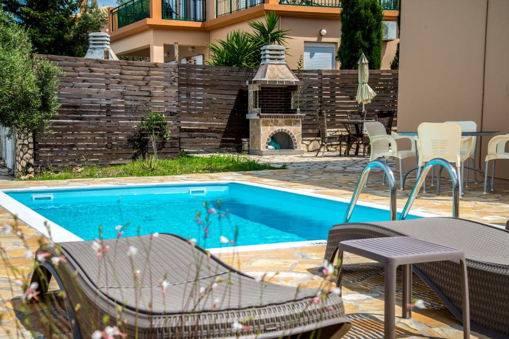 ツォウカラデスにあるIonides Villas Lefkadaの建物の隣にスイミングプール(テーブル、椅子付)
